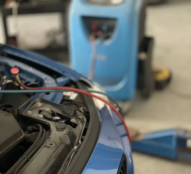 Air conditioning regas machine connected to a customer car at Ignite Autos — high and low side hoses on the engine bay