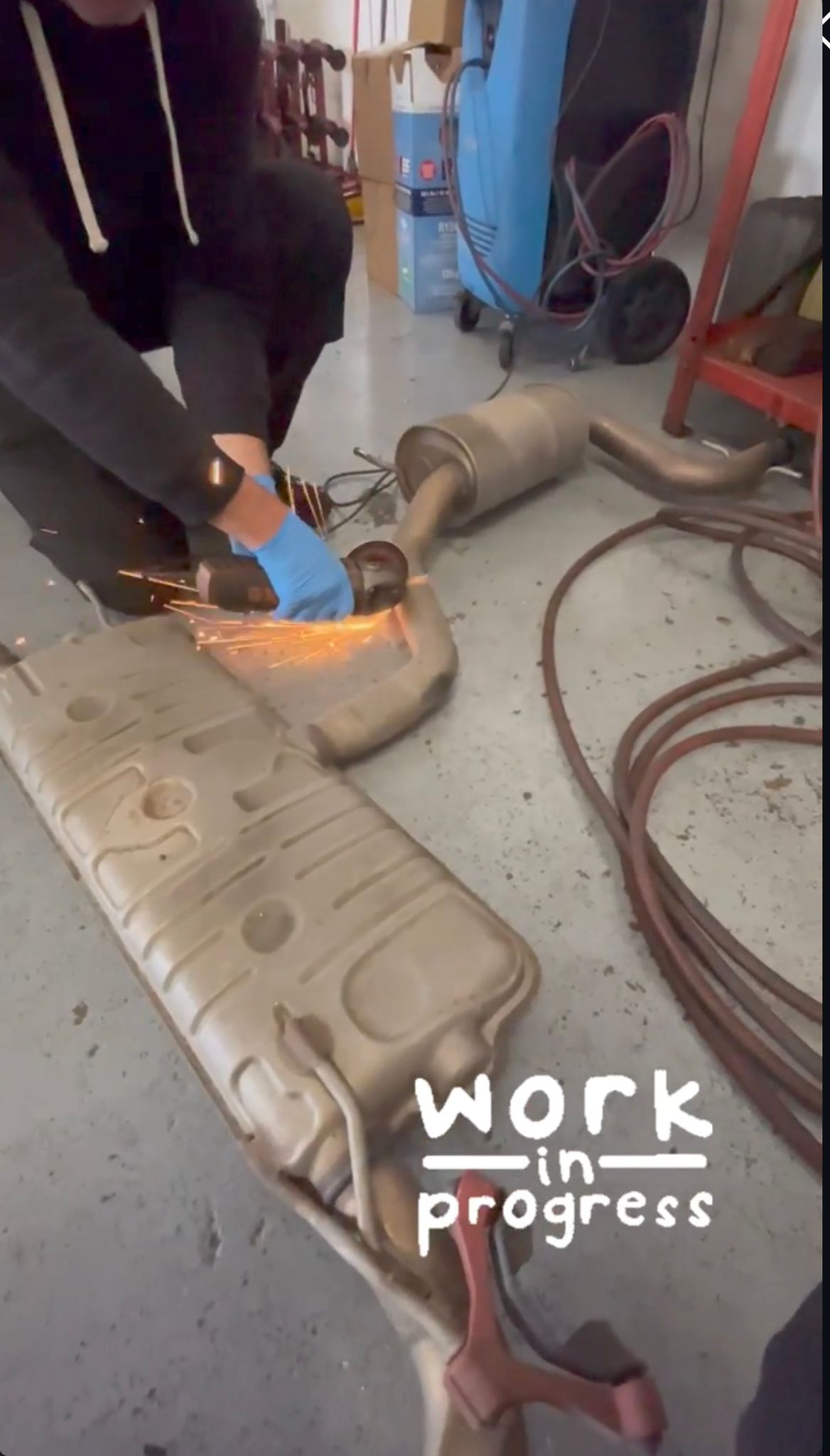 Technician cutting an OEM exhaust during a fitting at Ignite Autos