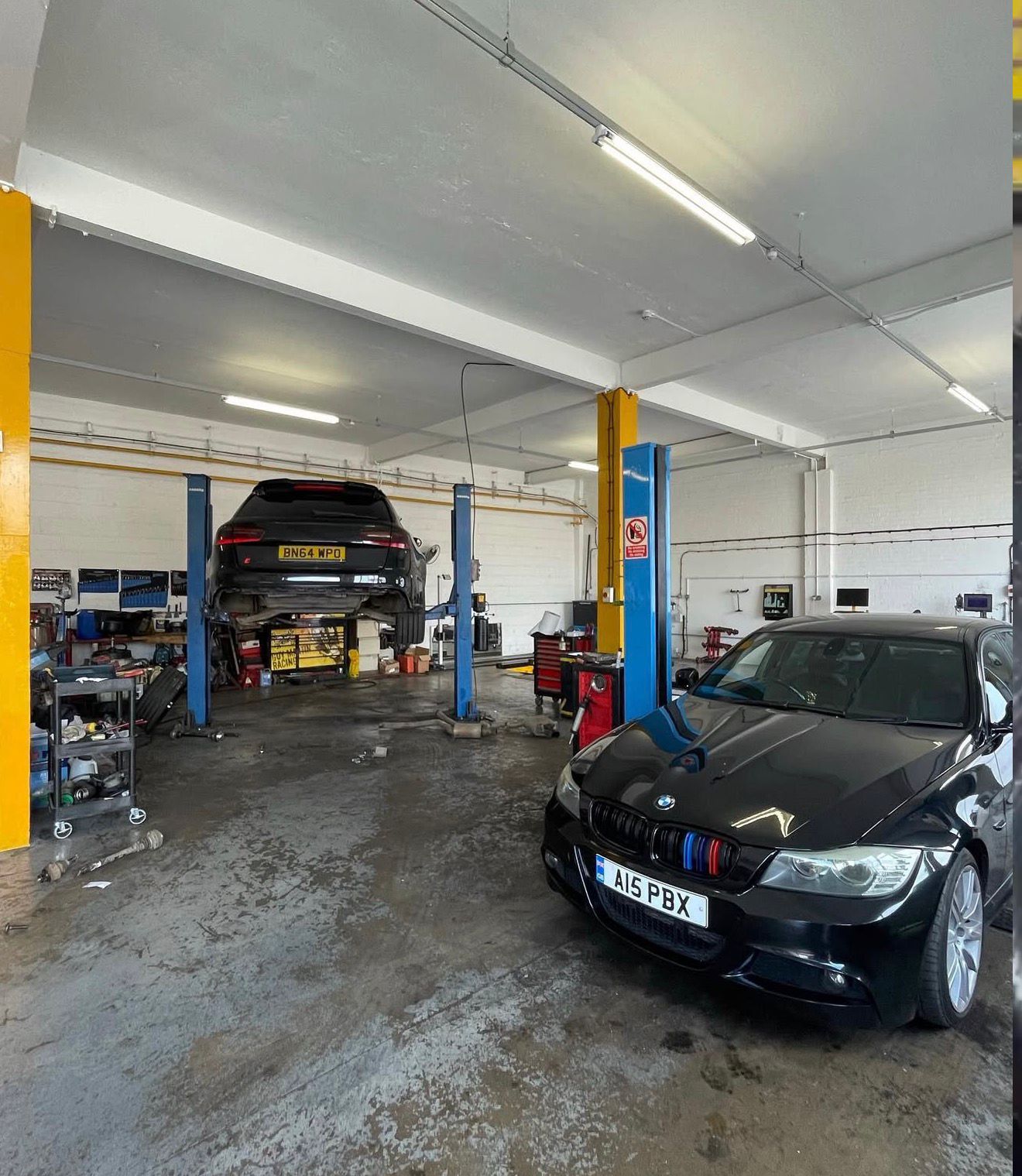 Audi on the two-post lift with a black BMW E90 335i parked alongside in the Ignite Autos workshop
